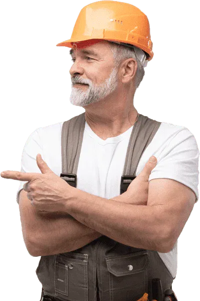 Senior male construction worker with a grey beard wearing an orange hard hat and grey overalls, pointing to the side against a white background.