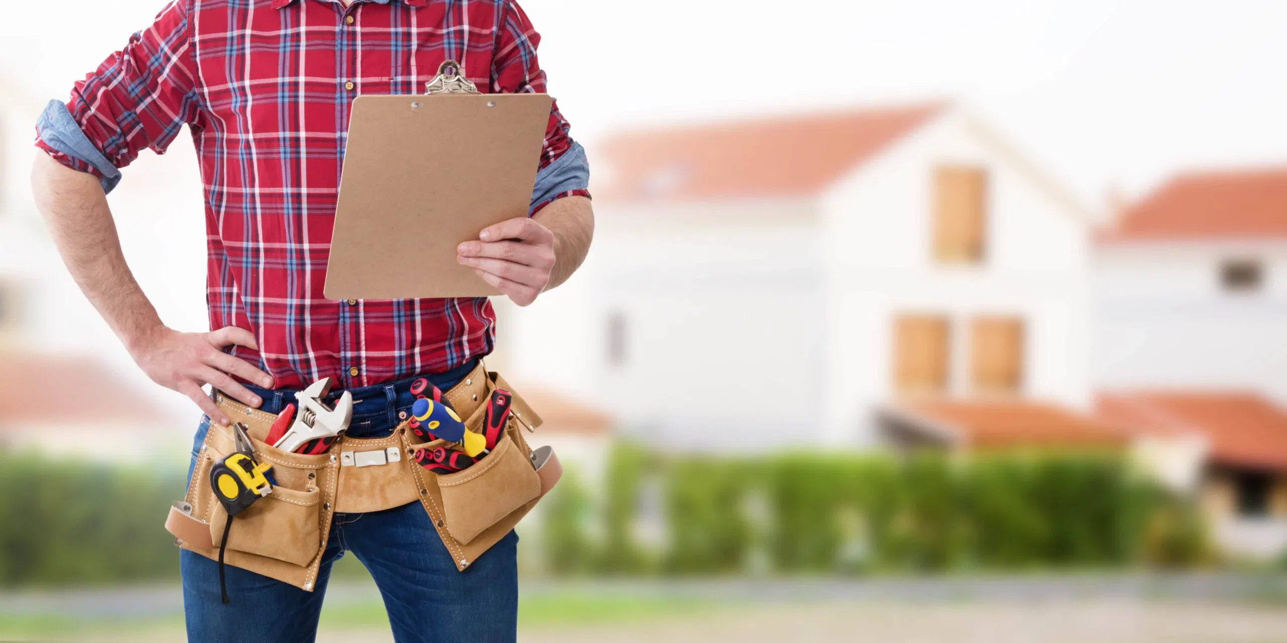 A professional home contractor wearing a tool belt and holding a clipboard, standing in front of a blurred residential house background.